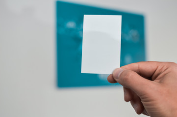 Closeup image of holding business card, person hand showing plain mock up space on professional office background. Businessman communication information