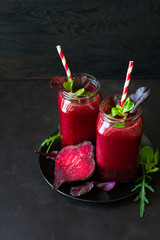 Fresh beetroot smoothie, beet, arugula and lettuce leaves on dark wooden background