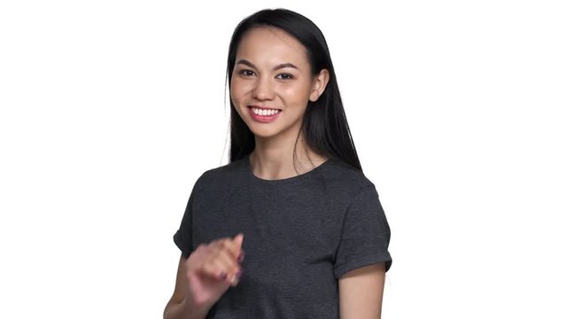 Portrait of playful flirting asian woman 20s in casual t-shirt with long hair showing her romantic feelings and blowing air kiss to you, isolated over white background. Concept of emotions