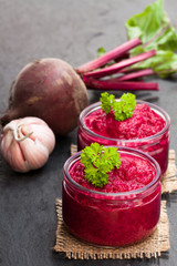 Beetroot  puree in glass jars on black stone background