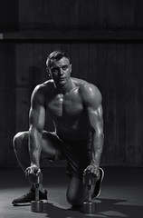 Fototapeta na wymiar Athletic man getting ready for fit training with dumbbells, black and white image