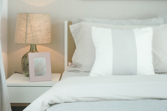 Close up pillows on bed with reading lamp and picture frame
