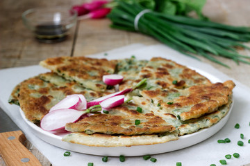 Homemade appetizing scallion pancakes with a bunch of green onions and radishes. Rustic style.