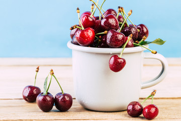 cherries in a white enamel mug on a wooden table, fresh cherry, seasonal berries, sweet cherry, ripe berries, berries in to the handle