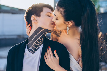 young stylish couple with tattoos kissing on outdoors