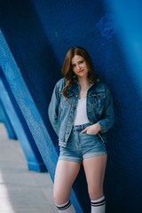Naklejka premium portrait of smiling stylish woman in denim clothes and high socks looking at camera