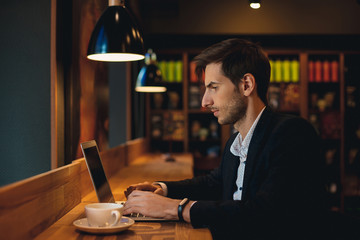 Confident man working on laptop having coffee