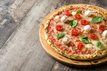 Pizza with tomatoes, cheese and basil on wooden table. Copyspace