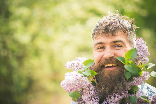 Bearded man smiling in countryside garden holding lilac branches. Male florist taking care of blooming orchard, spring time concept. Face of happy man on natural background