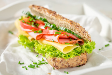 Tasty roll with ham, cheese and tomato for breakfast