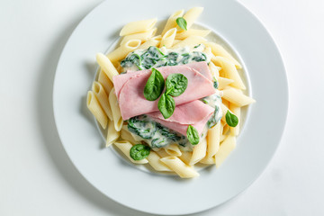 Tasty pasta with bechamel sauce, ham and spinach