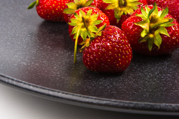 fresh ripe strawberries on black ceramic plate
