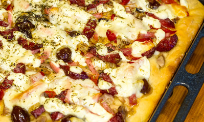 homemade pizza with peppers, plums, ham, sausage, cheese and spices, closeup