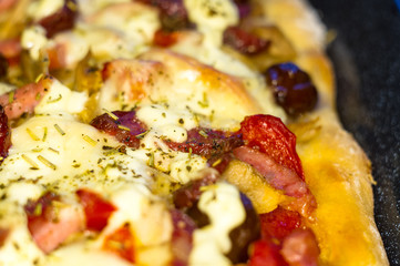 homemade pizza with peppers, plums, ham, sausage, cheese and spices, closeup