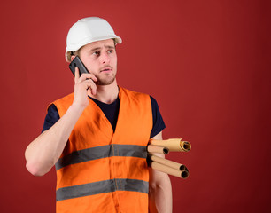 Architect concept. Man, foreman in helmet supervises construction on phone, red background....