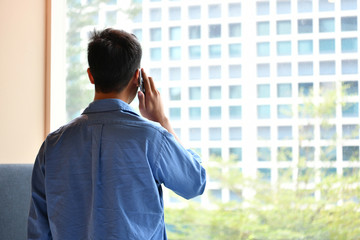 Young man talking on mobile phone while he standind in his room at home