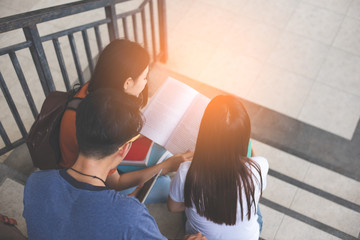 Group of Asian college student using tablet and mobile phone outside classroom. Happiness and Education learning concept. Back to school concept. People theme. Outdoors and Technology theme. Back view