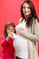 Pregnant woman with toddler girl holding baby shoes
