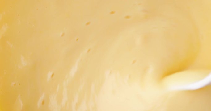 Top close view of fresh creamy homemade banana cream pudding being stirred with a white plastic spoon illuminated with window light.