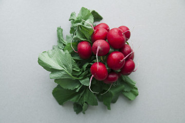 Heap of fresh radishes with tops and leaves on wooden rustic background
