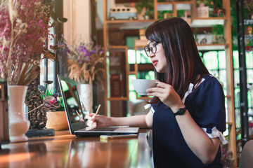 Asian business female working with laptop make a note in coffee shop like the background.