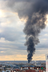 Fire in the city.  black column of smoke rises to sky.