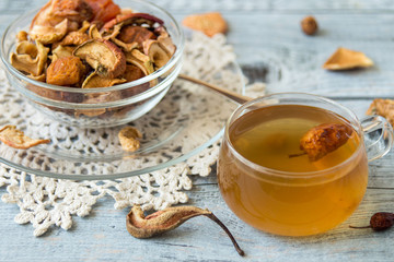 Mug with compote and a mixture of dried fruits in a small round glass bowl on an old wooden table. 