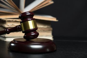 Judge gavel beside pile of books on wooden background