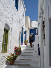Amorgos,Greece-August 4 ,2017.An old man is walking home through the narrow steps with the multi coloured windows and doors of Amorgos
