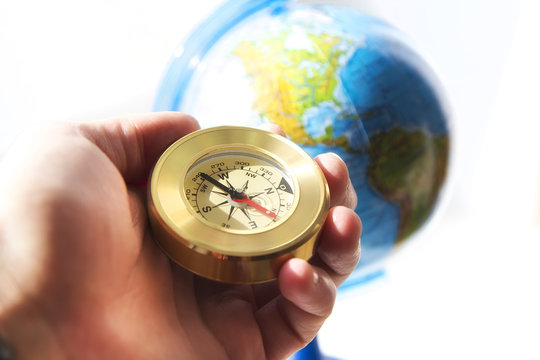 compass in man's hand with the globe on the background . travel and explore concept