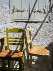 Two traditional multi colored chairs in front a wooden window