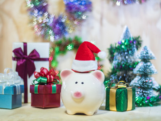 Piggy saving bank with Santa hat on wooden floor