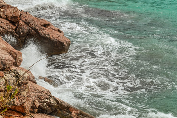 Huge stones in the sea and waves. On a sunny day. View from above. Montenegro. The Budva Riviera