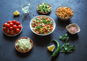 Summer vegetarian diet. Salad with chickpeas and vegetables on a black table.