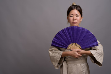 Young beautiful Kazakh woman against gray background