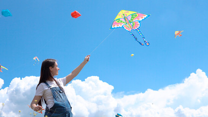 A, young, pregnant, girl, jumpsuit, launches, kite, against, blue, sky, clouds.