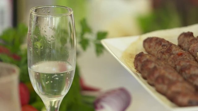 Dinner table served with lula kebabs and fresh vegetables. People enjoy Armenian style kebab at restaurant.