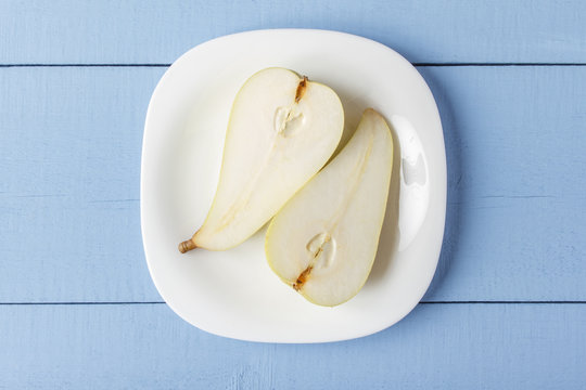 Sliced pears on wooden table. Organic fruits on white plate for dietary brakfast or dinner. Rustic lifestyle concept. Top view. Copy space