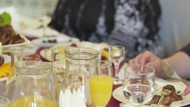 People celebrate holidays at festive dinner. Table served with lula kebabs vegetables and fresh fruit platter.