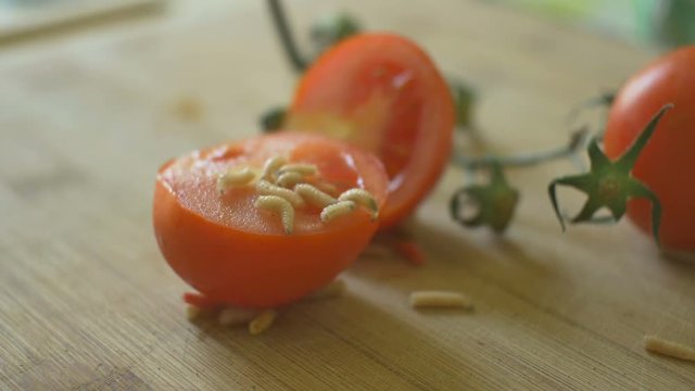 Worms crawling over tomatoes fruits in kitchen.