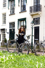 Woman girl parking vintage bicycle street old town sity black coat long curly hair enjoy sun spring glasses white house