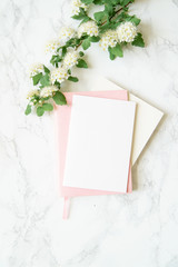 Flatlay in pink color with lilac flowers, notebooks and golden magnifier on marble background