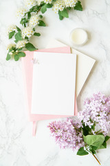 Flatlay in pink color with lilac flowers, notebooks and golden magnifier on marble background