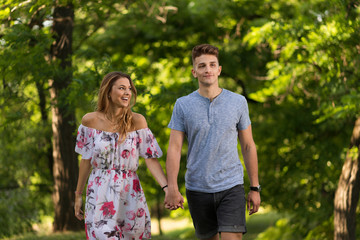 Obraz premium Smiling couple holding hands and walking in park.