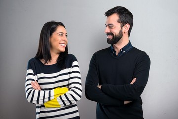 Couple with their arms crossed looking together on grey background