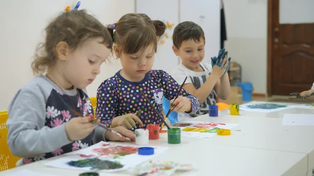 Children's developing a game room. Emotions of young children during entertaining classes. children paint with finger paints on white sheets of paper. children stretch their hands in the paint smeared
