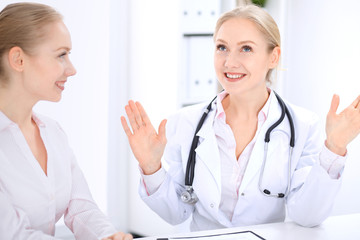 Blonde female doctor and patient talking in hospital office. Health care and client service in medicine