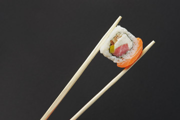 Holding roll with salmon and tuna with chopsticks