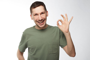 Fototapeta premium Attractive Caucasian man with beard opening mouth with joy showing ok sign being glad after meeting with woman he likes isolated over white background. Human facial expressions and emotions concept.