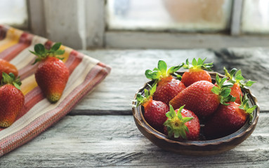 Fresh strawberries in a wooden bowl on a rustic wooden table